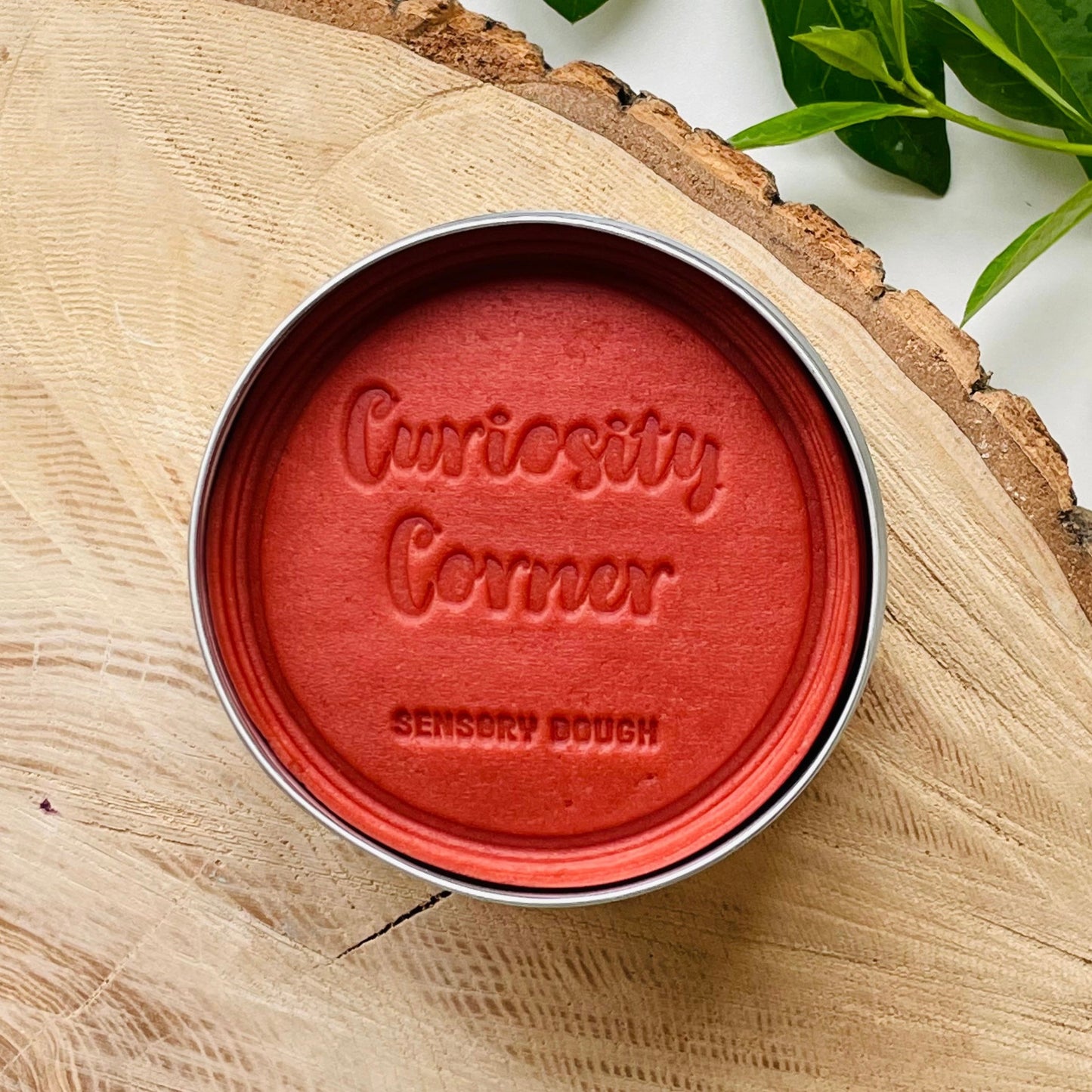 Rusty Red Sensory dough container with 'Curiosity Corner' branding on a wooden surface.