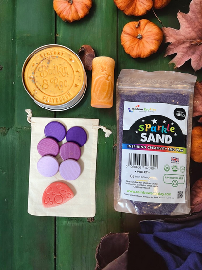 Cub & Bear Ltd sensory play kit featuring violet sparkle sand, orange dough, purple wooden discs, and a red mushroom.