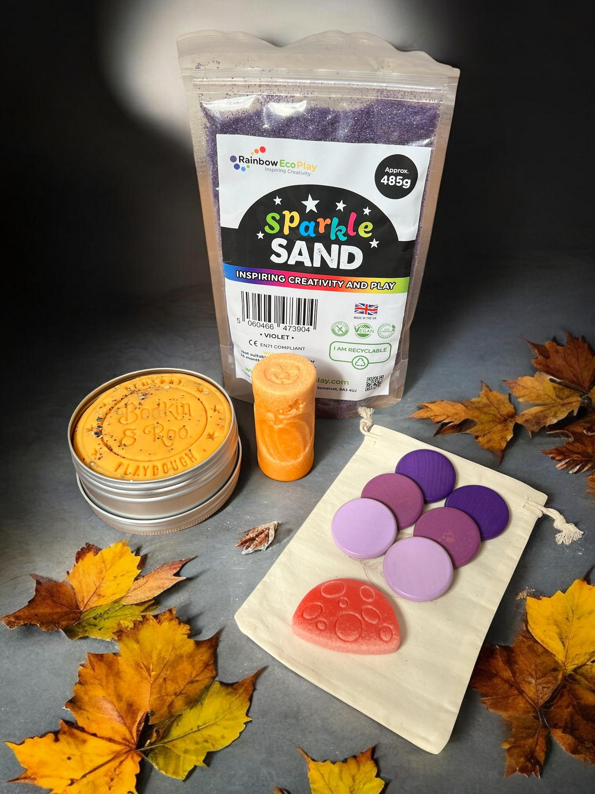 Cub & Bear Ltd sensory play kit with violet sparkle sand, orange playdough, purple wooden discs, and red mushroom toy.